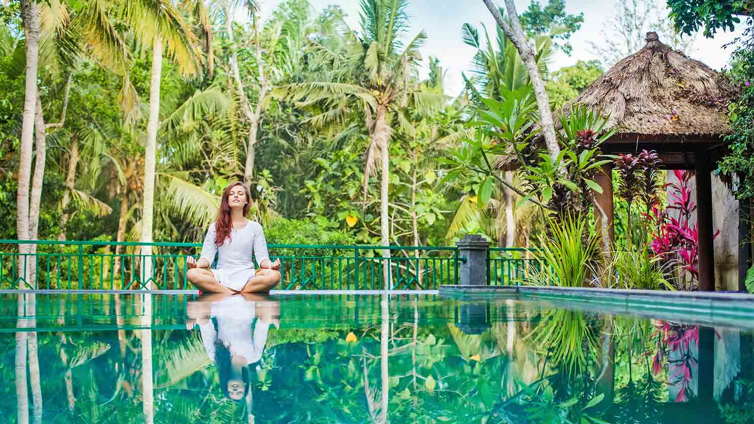 woman meditating by the pool at a yoga center abroad