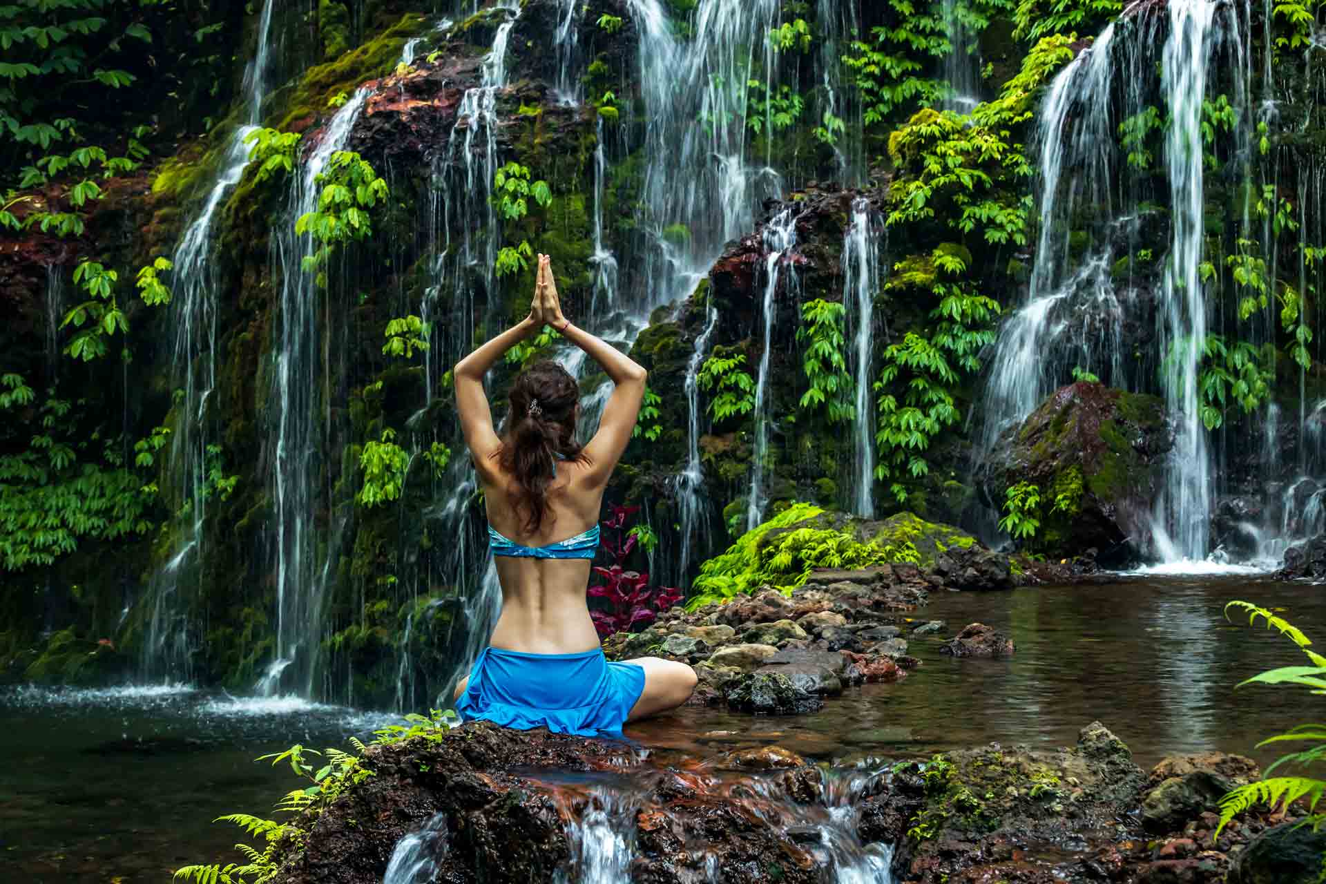 Woman doing yoga in Bali by a waterfall